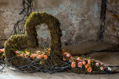 Floral arrangement with colorful rose flowers and wooden twigs with green natural heart on wood floorの写真素材