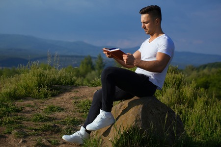 Young handsome serious man with muscular sexy body and bare chest sitting with laptop outdoor sunny day on blue sky backdropの写真素材