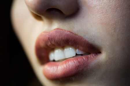 female lips with peach color lipstick on open mouth with white teeth closeupの写真素材