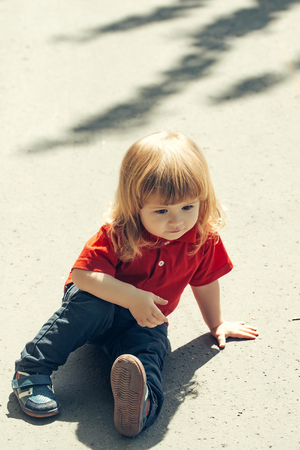 Adorable little boy stands up after the fallの写真素材