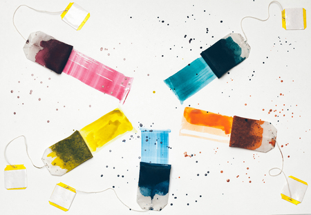 Colorful teabags drawing on white background with paint spots lying in round shapeの写真素材