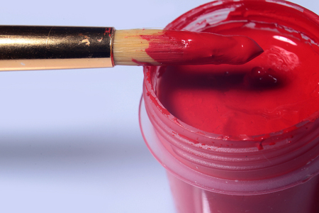 red gouache paint with brush on paintbox closeup on grey backgroundの写真素材