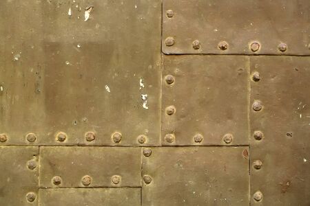 Old rusty grunge iron metal sheets assembled with rivets on armor textured background closeup