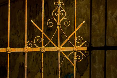 Old metal wrought decorative pattern on iron rusty vintage fence on dark background