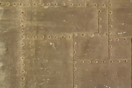 Old rusty grunge steel fragment of metal sheets assembled with rivets on armor textured backgroundの写真素材