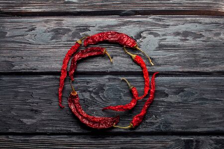 dried red chili pepper on dark textured wooden background in round shape, copy spaceの写真素材