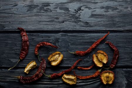 wrinkled dried red chili pepper and apples on dark textured wooden background in round shape, copy spaceの写真素材