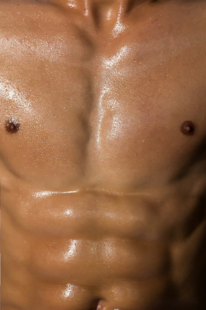 sexy muscular male torso six packs on wet body of athletic man training with bare strong chest, closeupの写真素材