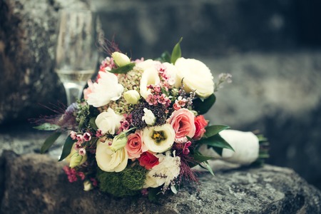 wedding bouquet of fresh rose lupine and other flowers white pink and violet colors with green leaves lying on grey stone backgroundの写真素材