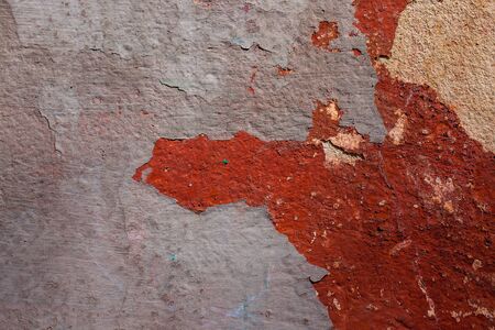 Old wall with plaster cracks and peeling paint on cement background