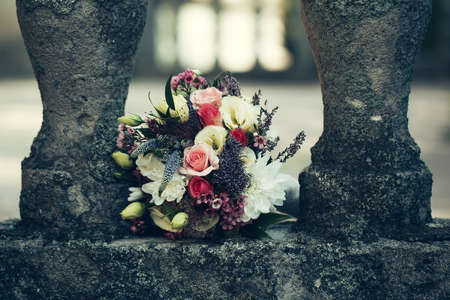 wedding bouquet of fresh rose lupine and other flowers white pink and violet colors with green leaves lying on grey stone backgroundの写真素材