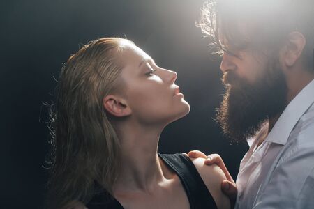 young sexy couple of pretty woman with blonde wet hair and handsome bearded man with long beard embracing on dark studio backgroundの写真素材
