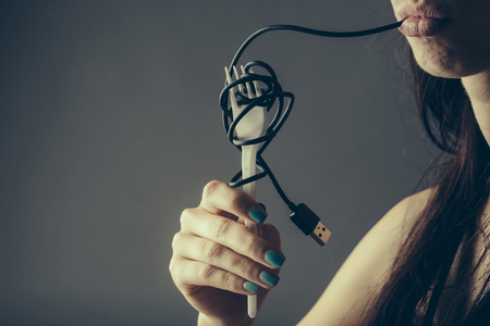 female mouth with sexy lips holding with finger usb flash wire cable for connection and white...
