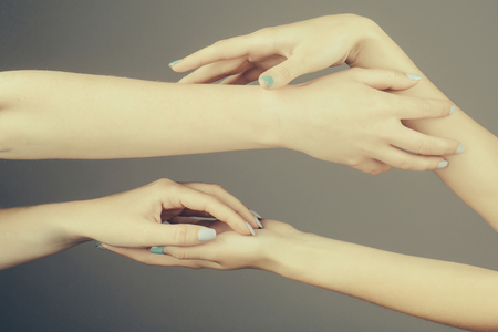 four female hands with soft tender skin and blue manicure holding and touching each other making massage on grey backgroundの写真素材