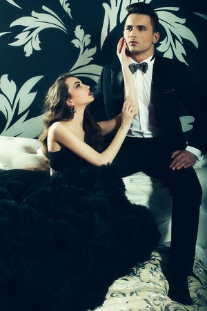 young handsome man in black suit and bow with pretty sexy woman in elegant evening dress with skirt and long curly hairの写真素材