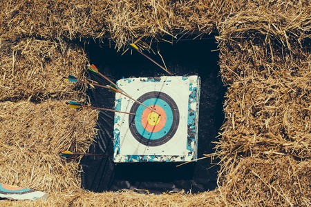 Archery target with arrows on rural shooting range outdoors on haystack backgroundの写真素材