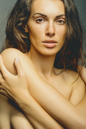 young sexy woman with pretty face and long brunette curly hair with bare shoulders and chest, closeupの写真素材