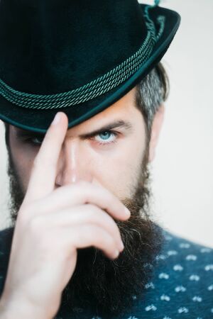 handsome bearded young man hipster or gentleman with long beard and mustache in stylish black retro hat on serious face in studio on white background, portraitの写真素材