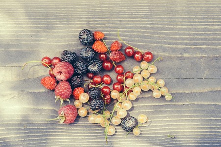 wild berries of red and white currant strawberry blackberry and raspberry on wooden background in...