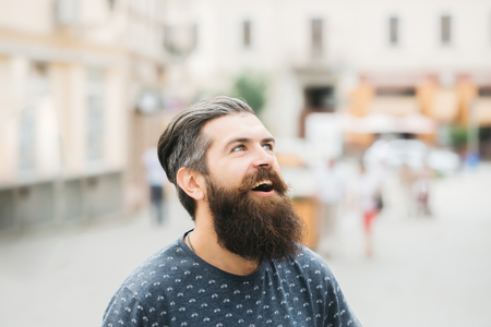 handsome sexy bearded young man hipster with long beard and mustache has stylish hair on smiling hairy face outdoor, closeupの写真素材