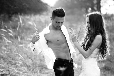 Young happy wedding couple of pretty woman and man undressing in field outdoor, black and whiteの写真素材