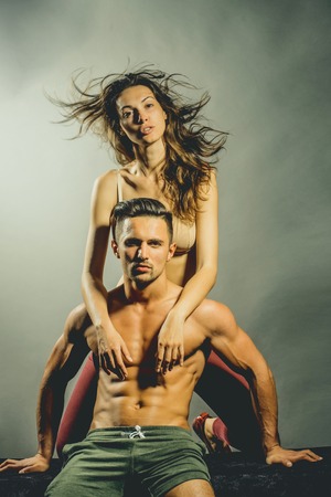 young sexy couple of pretty woman in beige bra with wet hair and handsome macho man with muscular torso and athletic body in studio on grey backgroundの写真素材