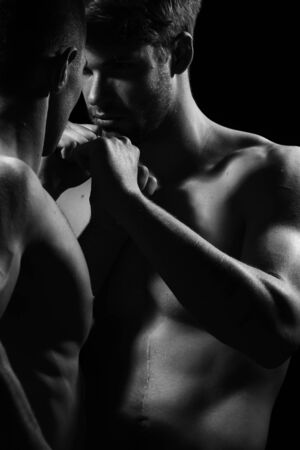 Young men boxing with sexy muscular body and bare torso in studio, black and whiteの写真素材