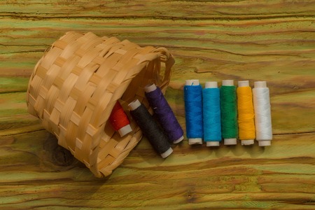 Bobbins of thread fall out of the weaven basketの写真素材