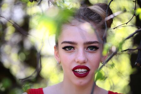 young pretty woman in the garden with fresh spring leaves on trees on blurred natural backgroundの写真素材