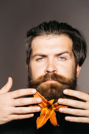 Attractive young bearded man with orange lilyの写真素材