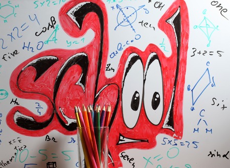 school text word painted graffiti with smiley eyes math equations and formulas on paper near colorful pencils in glassの写真素材