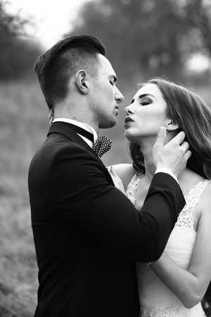 Beautiful bridal couple of young man embracing happy pretty woman outdoor, black and whiteの写真素材