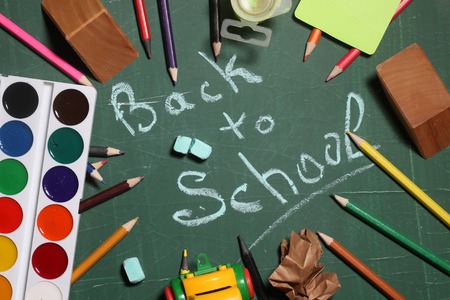 Back to school text word drawing by blue chalk in center and stationery colorful paints colored...