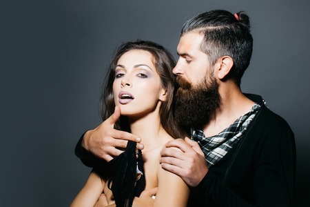 young couple of sexy woman with makeup on pretty face and brunette hair with bare shoulders on body and handsome bearded man with long beard holding fashionable bra in studio, copy spaceの写真素材