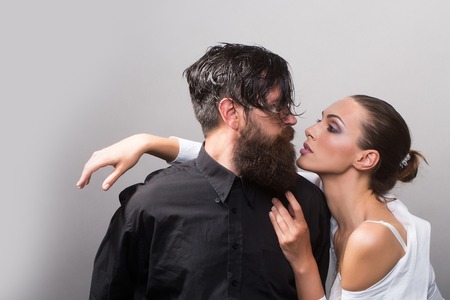 young sexy couple of woman with glamour makeup on pretty face in stylish shirt and bra near handsome bearded man with long beard and wet hair in studio on grey backgroundの写真素材