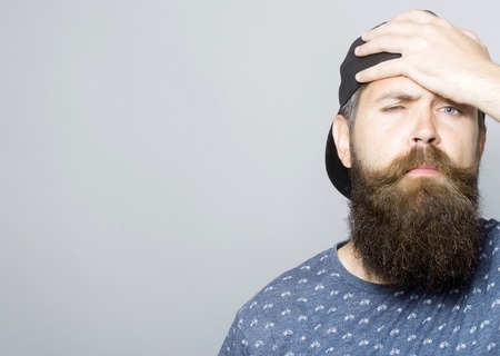 Close up of tired young attractive bearded guy. Portrait of young handsome man in a cap with long beard and moustacheの写真素材