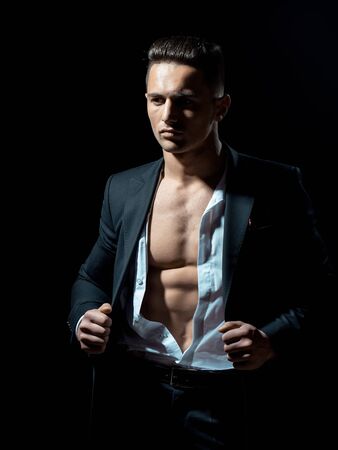 young handsome gentleman wearing fashion black suit in white open shirt with bare torsoの写真素材