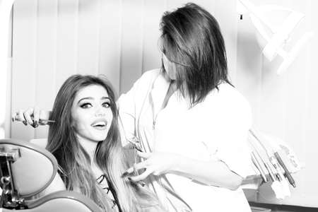 Scared young woman receiving dental checkup with doctor, black and whiteの写真素材
