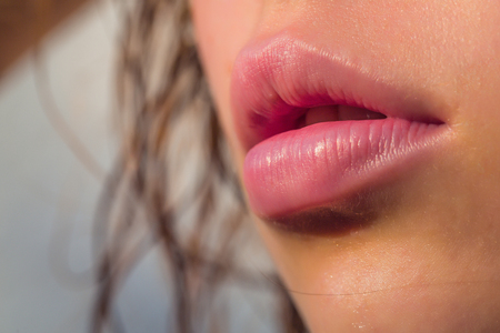 Female mouth with attractive sexy sensual lips vogue natural makeup with wet skin on background of hair closeupの写真素材