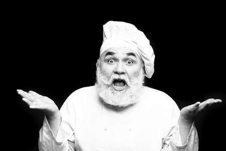 Bearded man cook in chef hat with surprised emotional face in studio, black and whiteの写真素材