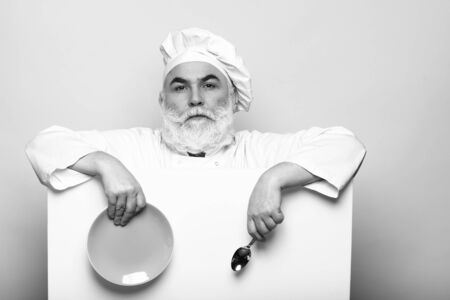 Happy bearded cook holding blank paper with spoon bottle and napkin, copy space, black and whiteの写真素材