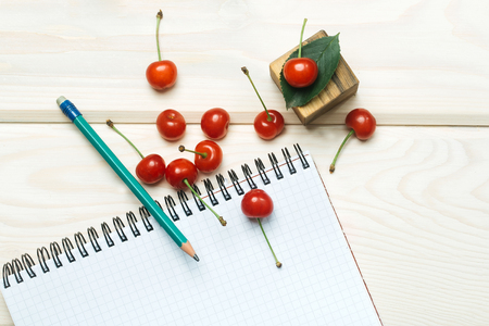 Notebook with pencil and juicy cherries. Healthy sneck for lunchの写真素材