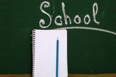 Spiral notebook with pencil in front of the green chalkboardの写真素材