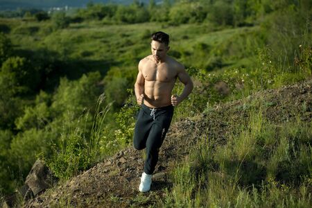 Handsome strong muscular athletic man working out and running outdoors in natureの写真素材