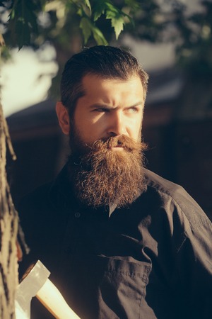 handsome bearded young man hipster with long beard and mustache has stylish hair on serious face...