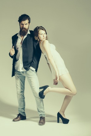 young couple of slim woman in underwear and shoes with handsome bearded man has beard in jacket on grey studio backgroundの写真素材