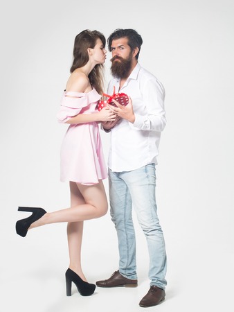 young couple of pretty girl with long hair and smiling face and handsome bearded man with beard holding gift or present box on valentines day isolated on whiteの写真素材