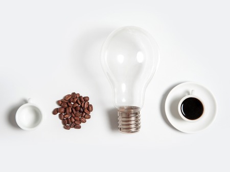white cup of coffee drink or beverage with lamp or light bulb near roasted beans and empty mug isolated on white backgroundの写真素材