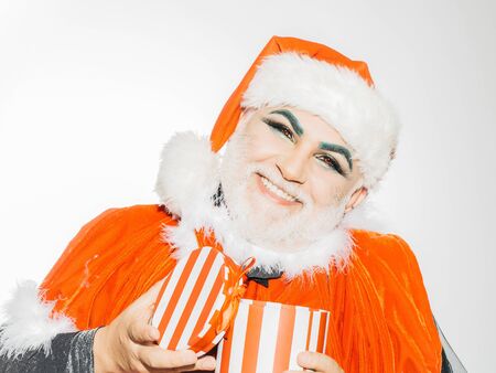 New year man with happy smile on face with makeup and beard in red santa claus xmas costume and hat...