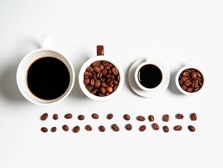 four white cups of coffee drink or beverage with roasted brown beans in line isolated on white backgroundの写真素材
